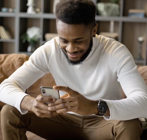 A man sat down texting on a phone